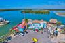 Waterfront commercial property featuring direct maritime access, a thatch-roof structure, paved parking area, and multi-level rooflines
