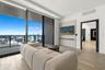 Floor-to-ceiling sliding glass doors, private balcony with metal railing, light wood-finish flooring, and a built-in wall panel with integrated shelf