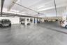Covered parking garage featuring concrete flooring, structural support columns, and overhead linear lighting fixtures
