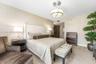 Geometric patterned wall covering, neutral-toned flooring, and a modern brushed-metal drum chandelier