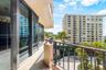 Covered balcony featuring expansive glass sliding doors, stone-finish flooring, and a metal railing