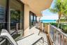 Covered balcony featuring tile flooring, full-height glass sliding doors, and metal railings, overlooking the ocean