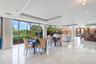 Open-concept interior featuring polished stone flooring, recessed tray ceilings, floor-to-ceiling windows with wood-finish frames, and a built-in wet 