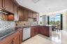 Kitchen featuring dark wood cabinetry, a mosaic tile backsplash, solid surface countertops, stainless steel dishwasher, and polished stone flooring
