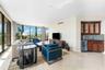 Floor-to-ceiling windows, polished stone flooring, and a built-in wet bar featuring dark wood cabinetry, glass-front upper cabinets, a mosaic tile bac