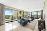 Floor-to-ceiling glass walls, polished stone flooring, and expansive wrap-around balcony with metal railing