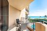 Covered balcony featuring stone-finish flooring, metal railing, and ocean scenery