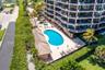 Multi-story high-rise featuring a kidney-shaped pool, separate spa, tile-roofed cabana, and manicured landscaping
