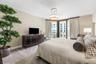 Geometric pattern wall covering, neutral carpeting, three-light drum pendant fixture, and sliding glass doors with access to an exterior balcony