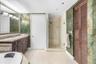 Bathroom featuring a dark wood-finish vanity with a stone countertop, an oversized wall mirror with decorative trim, a walk-in glass-enclosed shower, 