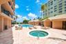 Community pool area featuring an in-ground spa, paver deck, and covered poolside cabanas