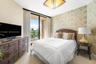 Floor-to-ceiling glass sliding doors opening to a private balcony, patterned wall covering, flush-mount geometric lighting fixture, and carpeted floor