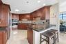 Kitchen featuring dark wood cabinetry, integrated stainless steel double wall ovens, a multi-tone tile backsplash, dark stone countertops, and a break