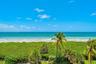 Oceanfront perspective featuring a sandy beach, coastal vegetation, and mature palm trees
