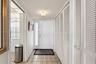 Entryway featuring a white paneled door with a vertical glass sidelight, floor-to-ceiling white louvered-style closet doors, patterned tile flooring, 