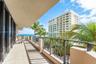 Covered balcony featuring tile flooring and metal railings, overlooking palm trees and the ocean