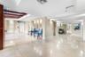 Spacious lobby featuring polished stone flooring, recessed ceiling lighting, a wood-beam architectural detail, and a decorative alcove with vertical w