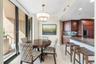 Open-concept kitchen area featuring dark wood cabinetry, stone countertops, breakfast bar, tile backsplash, and floor-to-ceiling glass panel walls