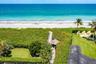 Oceanfront property featuring direct beach access via a private boardwalk, a covered gazebo, mature tropical landscaping, and a manicured lawn