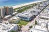Corner lot featuring expansive grass grounds and mature palm trees, positioned within an urban coastal setting