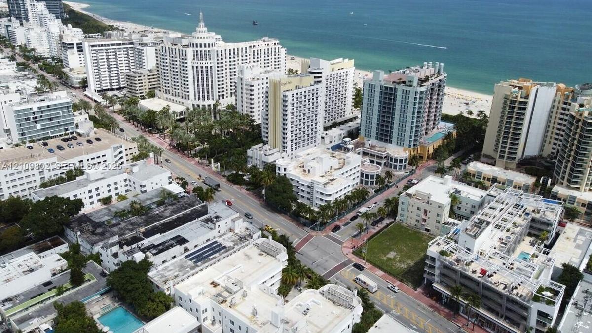 Aerial perspective of urban coastal surroundings featuring multi-story high-rise architecture, proximity to the coastline, paved thoroughfares, and ma
