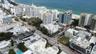 Aerial perspective of urban coastal surroundings featuring multi-story high-rise architecture, proximity to the coastline, paved thoroughfares, and ma