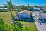 Waterfront property featuring a wood deck, structural pier, expansive lawn, and mature palm trees
