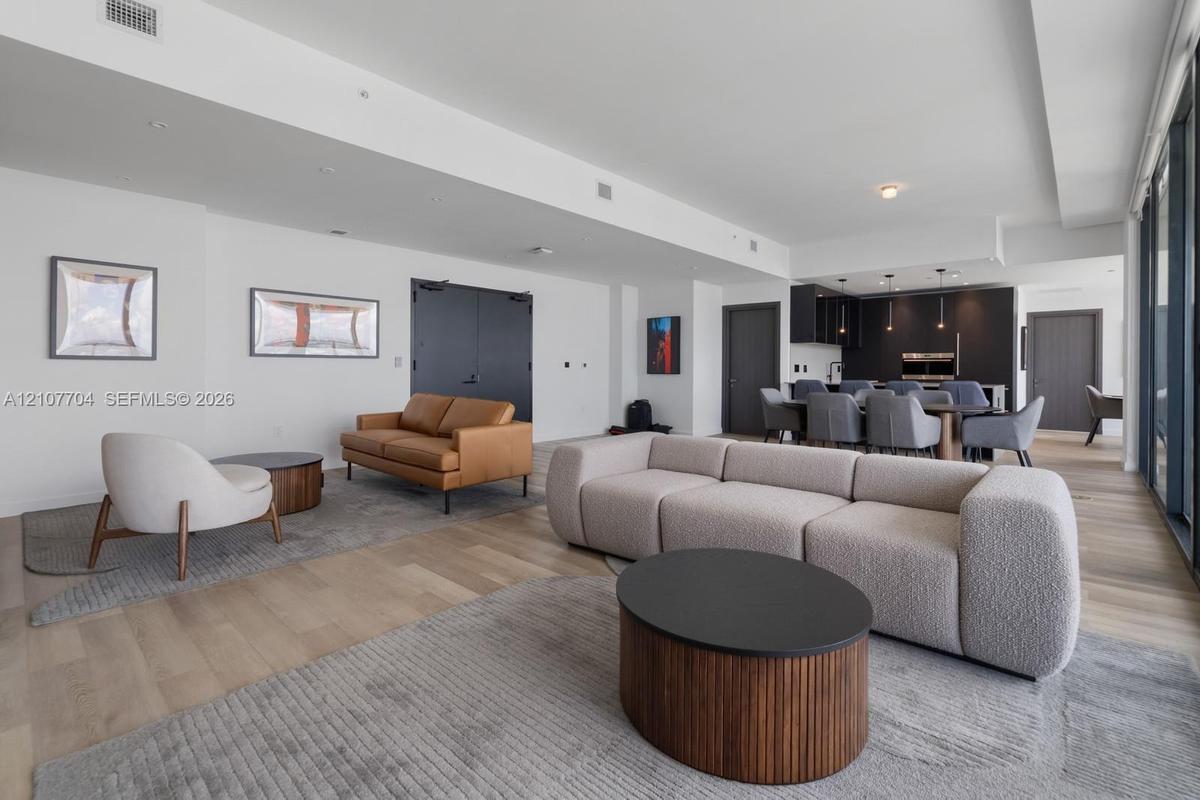 Open-concept floor plan featuring wood-finish flooring, high ceilings, recessed lighting, and kitchen cabinetry with integrated appliances