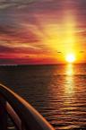 Coastal balcony featuring a structural railing overlooking a sunset over the ocean