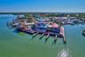 Waterfront property featuring multiple boat slips, thatch-roofed outdoor covered pavilions, and expansive wood-plank decking