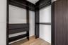 Built-in closet system featuring dark wood-finish cabinetry, integrated shelving, tiered hanging rods, and drawers, complemented by light wood-finish 