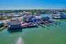 Waterfront commercial property featuring multiple thatched-roof structures, expansive wooden deck space, and private boat slips