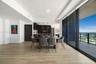 Open-concept floor plan featuring wood-finish flooring, floor-to-ceiling glass sliding doors, a balcony, and built-in cabinetry with integrated applia