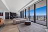 Floor-to-ceiling glass windows, expansive private balcony, wood-finish flooring, and integrated cabinetry