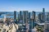 Aerial perspective of the metropolitan skyline, featuring high-rise glass-facade structures, surrounding waterway access, and urban infrastructure