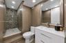 Modern bathroom featuring a walk-in glass-enclosed shower with mosaic stone accent tile, white vanity cabinet with an integrated sink, sleek chrome fi