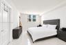 Bright bedroom featuring polished tile flooring, crisp white walls, and a large window