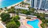 Oceanfront grounds featuring a swimming pool, multiple poolside cabanas, manicured landscaping, and direct beach access