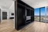 Custom-built dark finish storage cabinetry featuring integrated drawers and hanging rods, light-toned wood-finish flooring, and floor-to-ceiling windo
