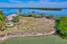 Waterfront lot featuring a concrete seawall, expansive grounds, and a thatched-roof pavilion
