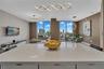 Expansive quartz island with white cabinetry, floor-to-ceiling windows, and contemporary sculptural lighting fixtures