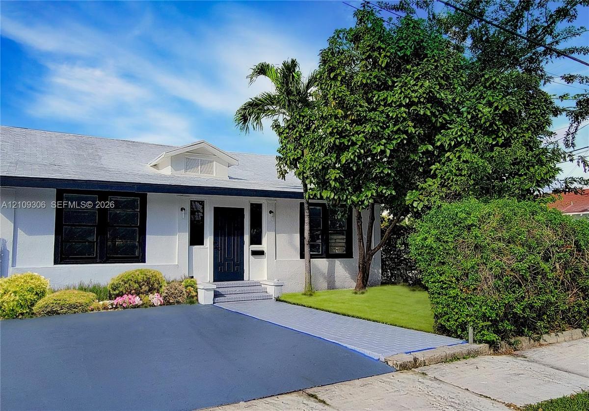 Stucco exterior with contrasting dark window frames, gabled roofline, front entry door, and paved driveway