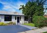Stucco exterior with contrasting dark window frames, gabled roofline, front entry door, and paved driveway