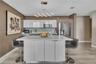 Kitchen featuring a central island with a quartz countertop, high-gloss white cabinetry, stainless steel appliances, a geometric LED pendant light, an