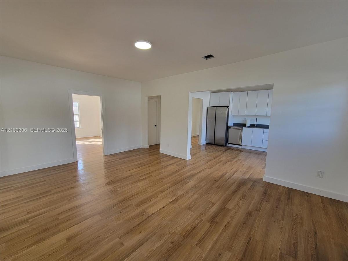 Open-concept interior featuring wood-finish flooring, white flat-panel cabinetry, stainless steel kitchen appliances, and recessed lighting