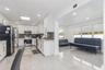Kitchen featuring white shaker cabinetry, stone-finish countertops, stainless steel appliances, and large-format tile flooring