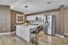Kitchen featuring wood-finish cabinetry, a central island with a stone-composite countertop, stainless steel appliances, and wood-finish flooring