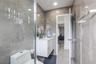 Full-height stone-finish wall tile, floating white vanity, recessed ceiling lighting, glass-enclosed shower, and polished stone-finish flooring