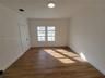 Interior room featuring wood-finish flooring, white walls, double-pane windows with horizontal muntins, and a flush-mount ceiling light fixture