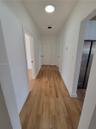 Hallway featuring wood-finish flooring, white walls, and flush-mount ceiling lighting